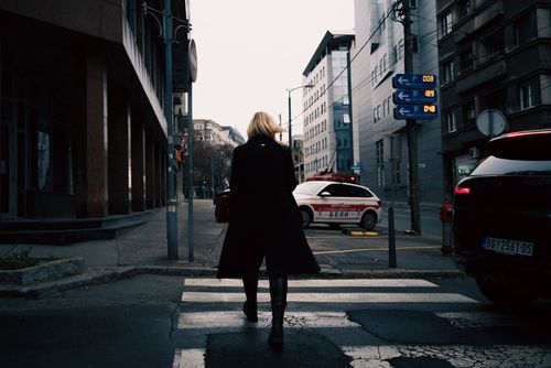 Free Urban scene in Belgrade, Serbia, with a woman crossing a street on a cloudy day. Stock Photo