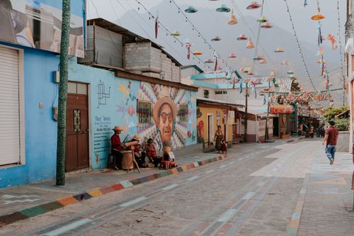 Free A lively street adorned with colorful murals and hanging decorations in a quaint neighborhood. Stock Photo