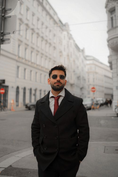 Free Man in black coat and sunglasses walking in a European city street. Stock Photo