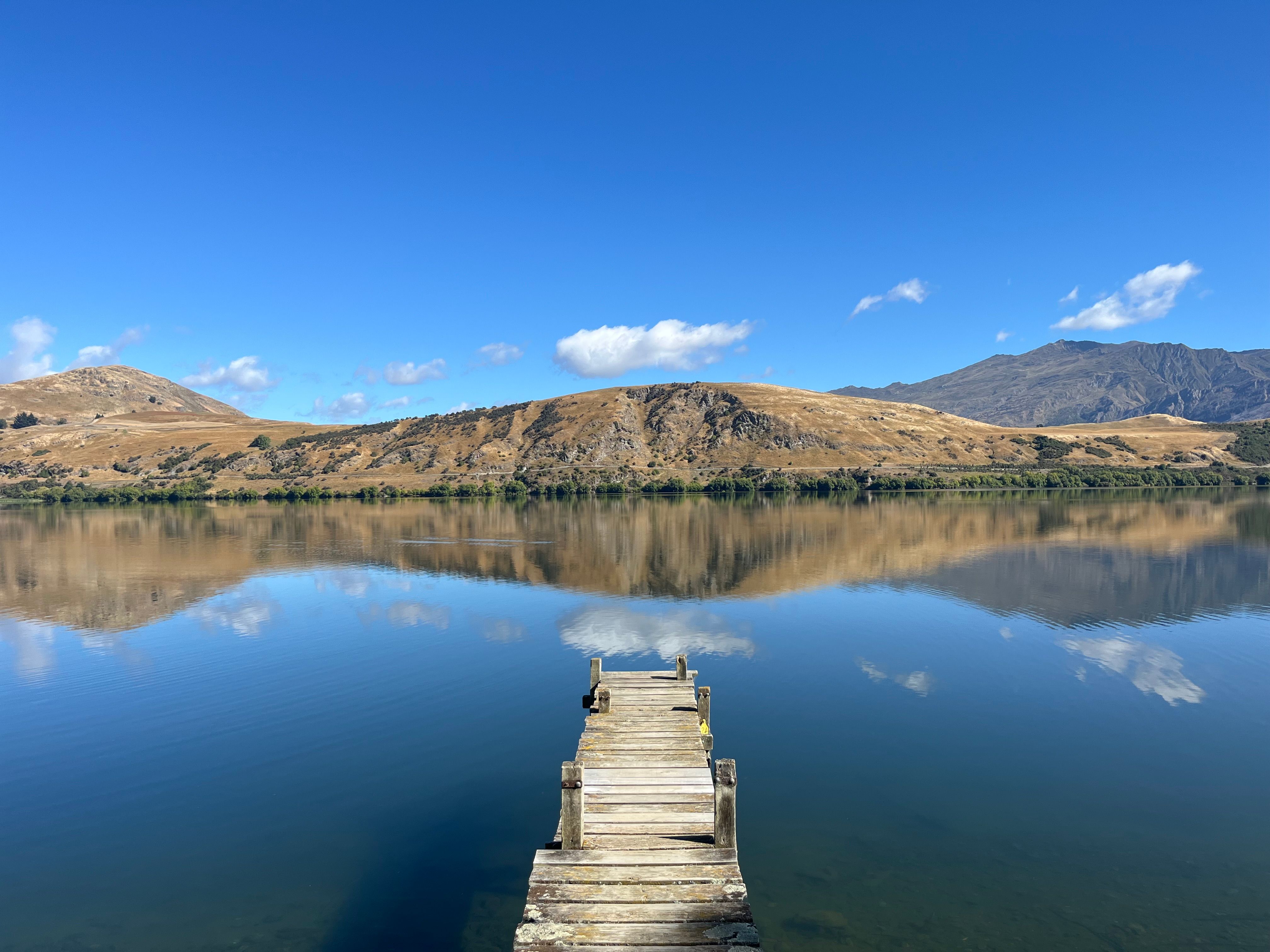 Serene Lake View with Wooden Dock and Mountains · Free Stock Photo