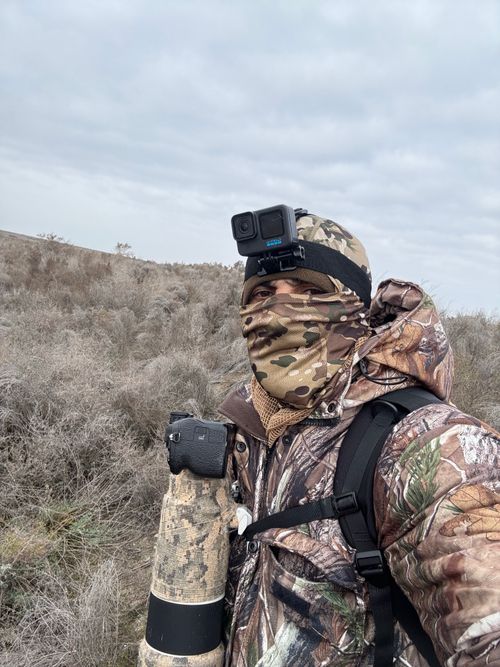 Free Photographer in full camouflage gear with camera in wild natural setting. Stock Photo