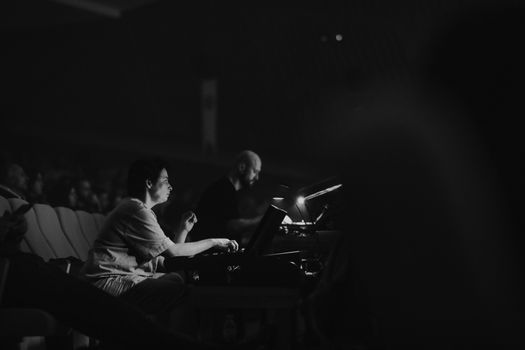 Sound engineer controlling audio during a live concert in a dimly lit theater.