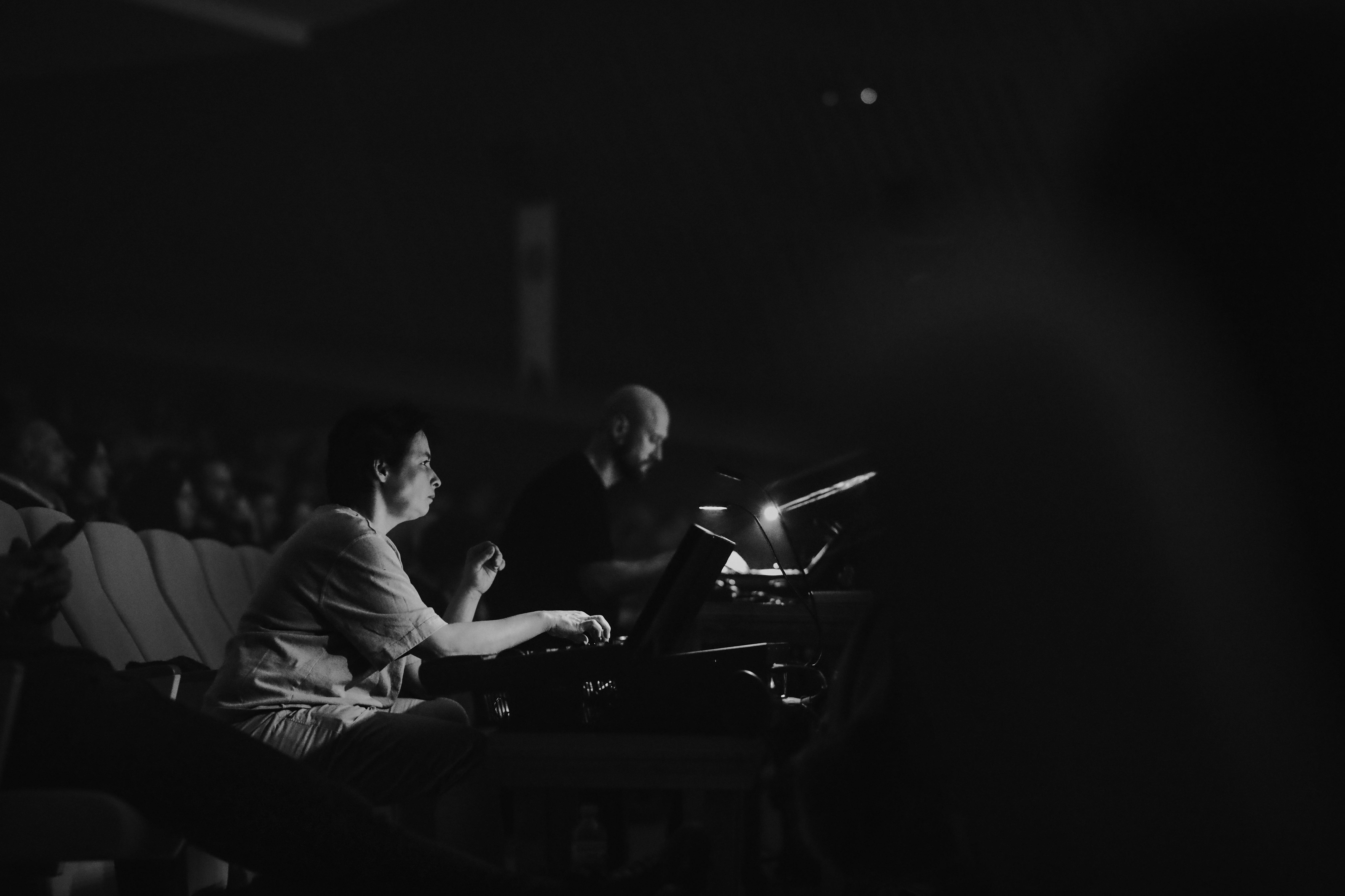 Gratuit Ingénieur du son contrôlant l'audio lors d'un concert en direct dans un théâtre faiblement éclairé. Photos