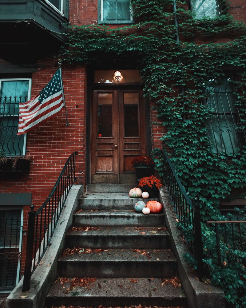 Historic Boston townhouse with an American flag and autumn pumpkins by the front door