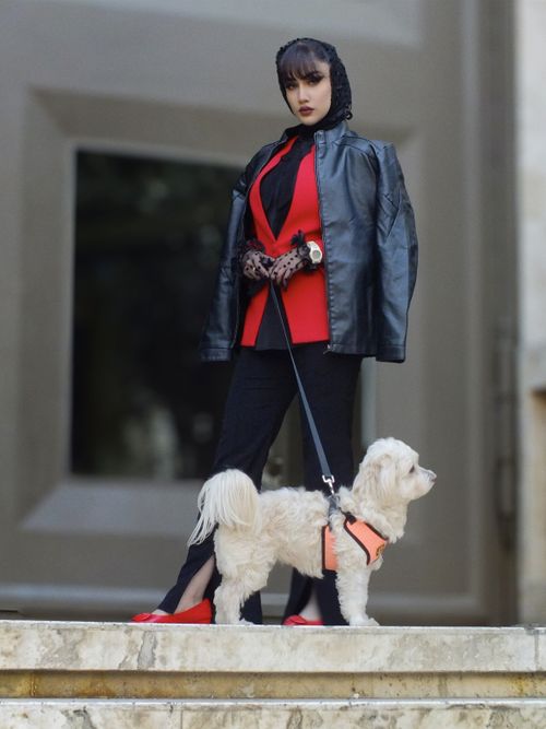 Free A fashionable woman poses with her dog in an urban environment, showcasing modern style. Stock Photo