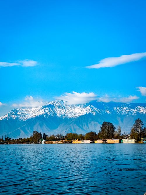 Free Captivating landscape featuring majestic snow-capped mountains and a serene lake under a clear blue sky. Stock Photo