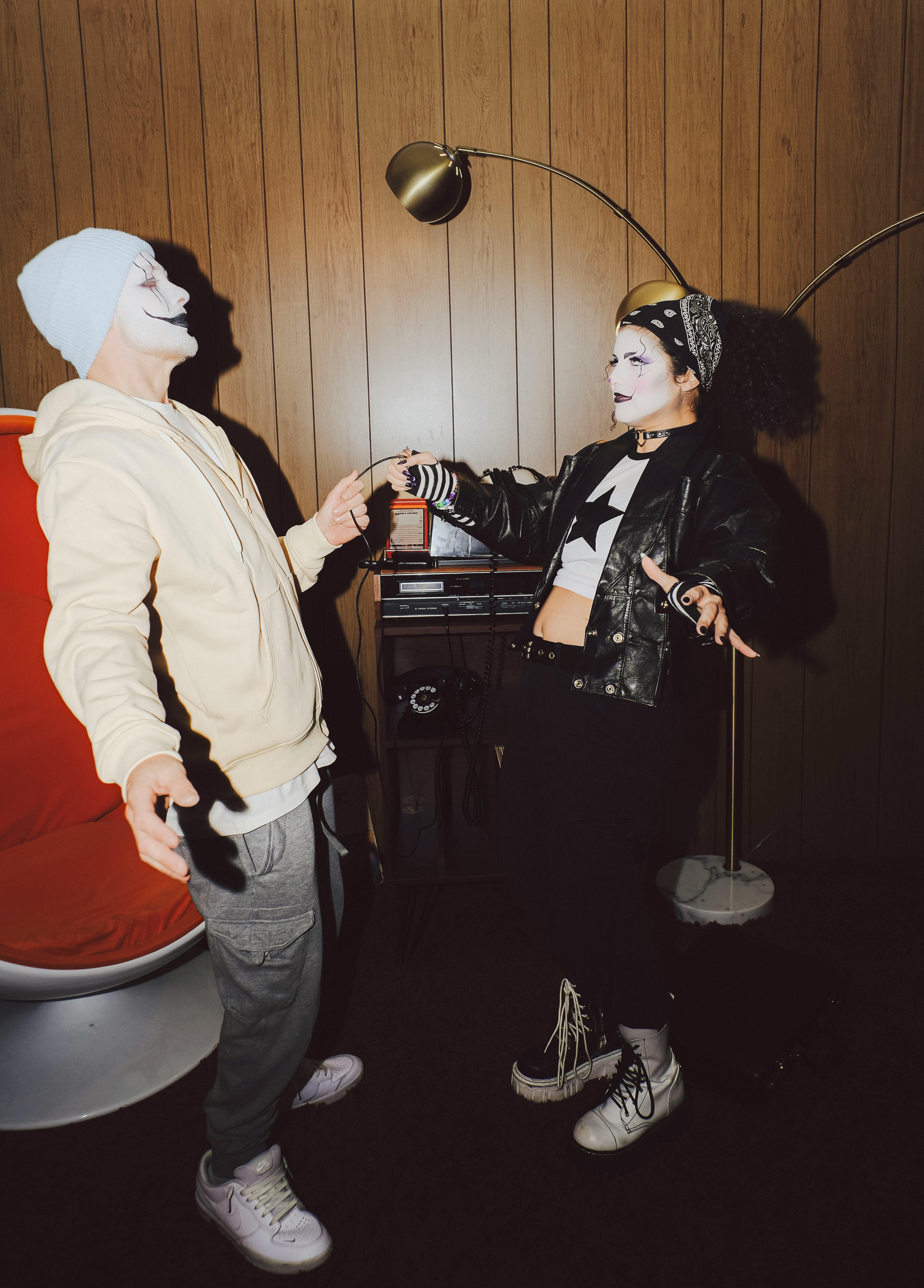 Two adults in costume and face paint having fun indoors at a party.