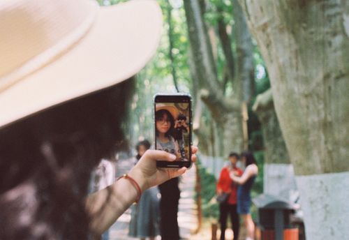 Free Woman in sun hat taking selfie with smartphone in a park. Stock Photo
