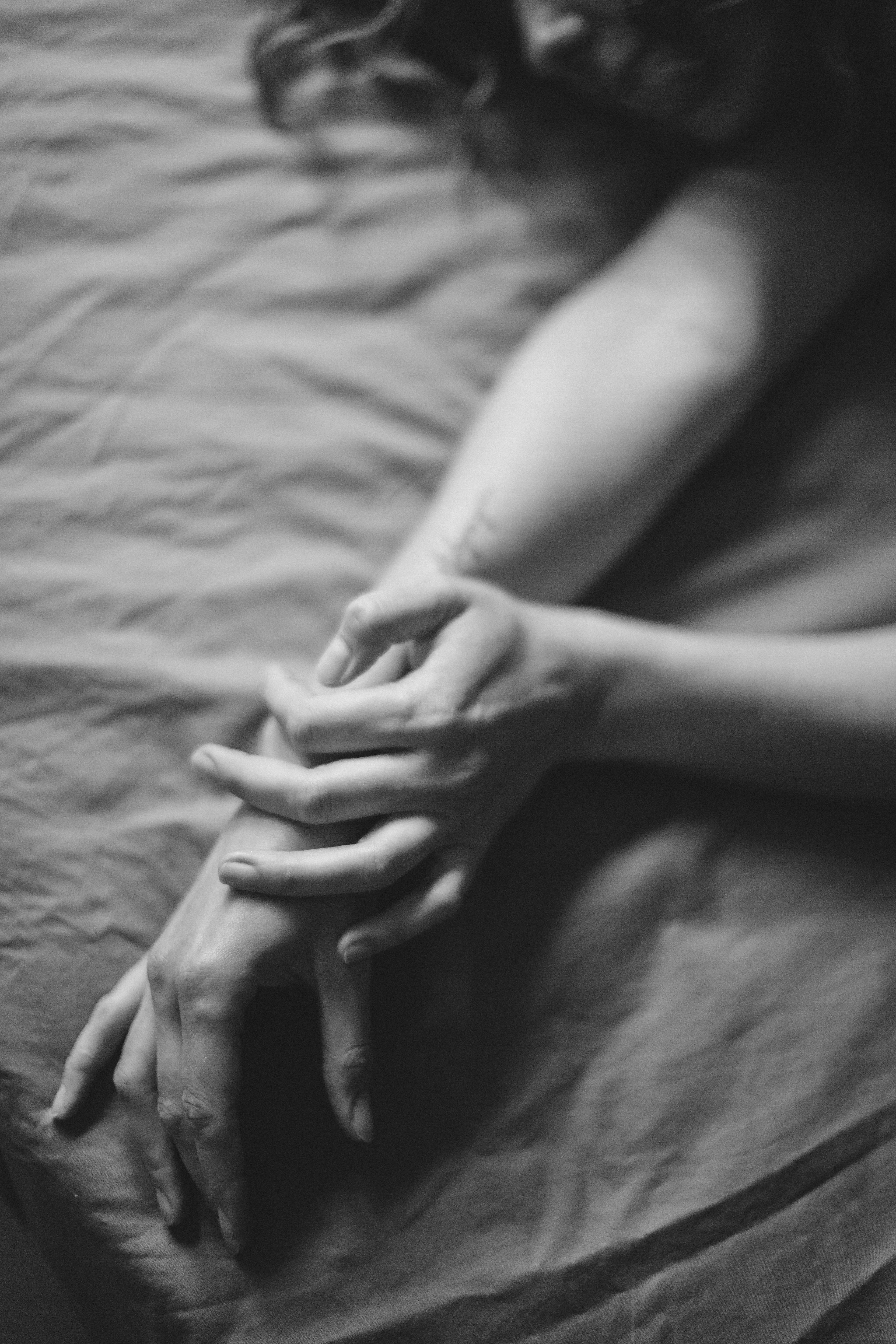 黑白照片中，双手在柔软的织物上交织，描绘情感