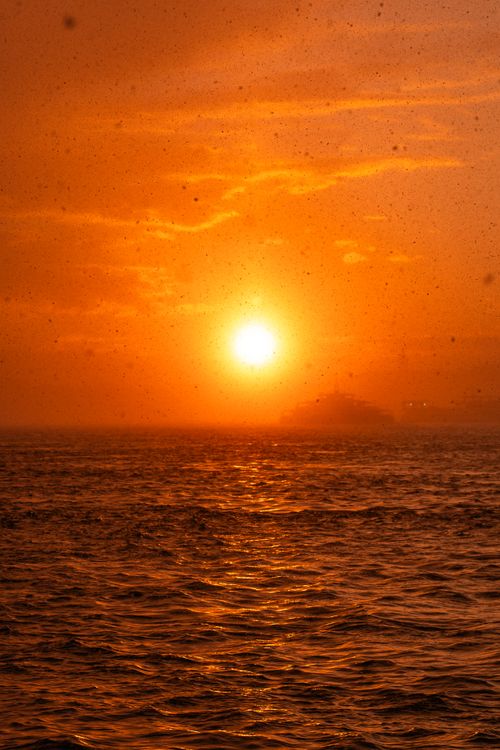 Free Stunning golden sunset over the ocean with gentle waves and a warm glow. Stock Photo