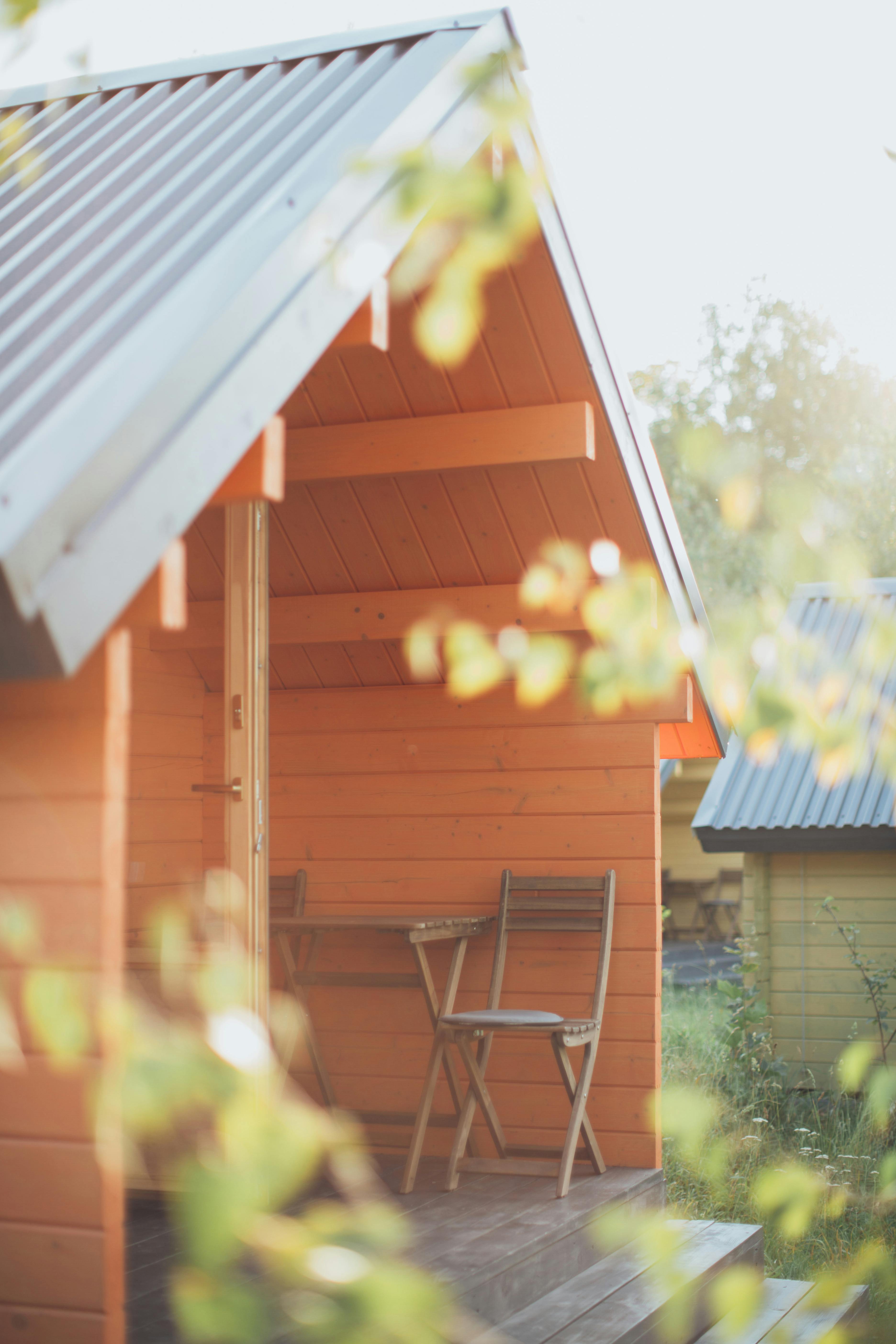 chair beside table in front of an orange wooden shed