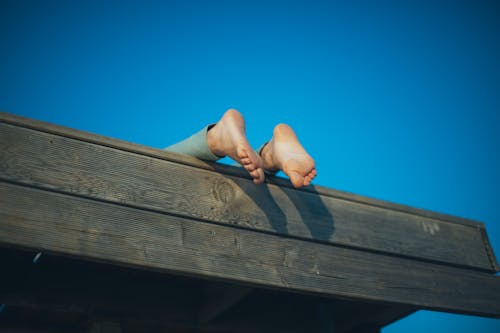 Free Photo of Person's Feet on Wooden Roof Stock Photo