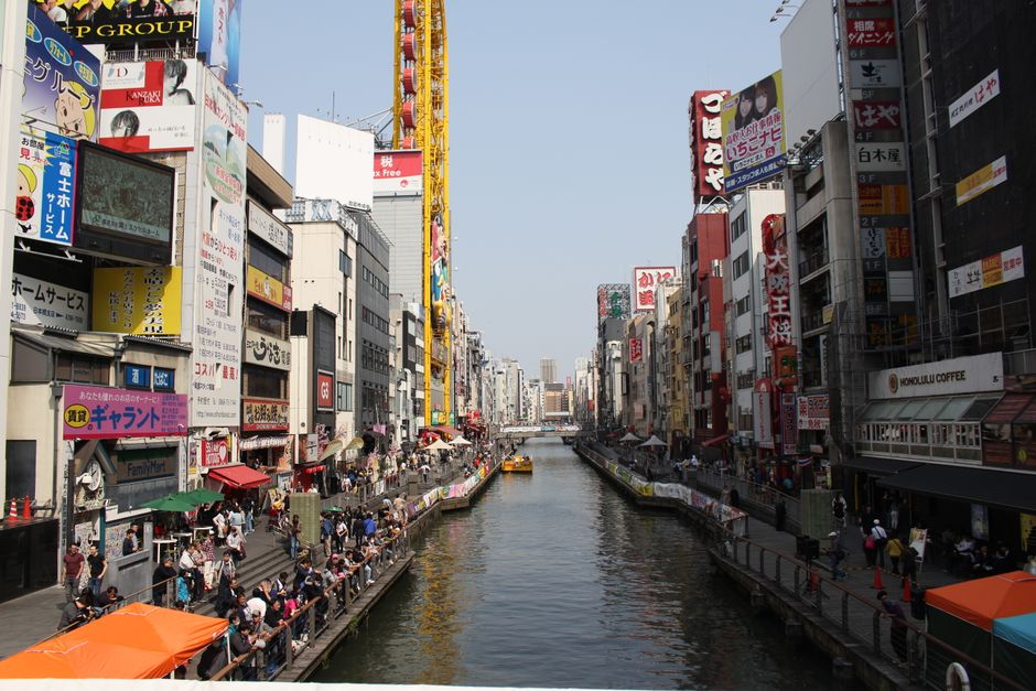 Vibrant street scene along Dotonbori Canal in Osaka, Japan featuring colorful signage.
