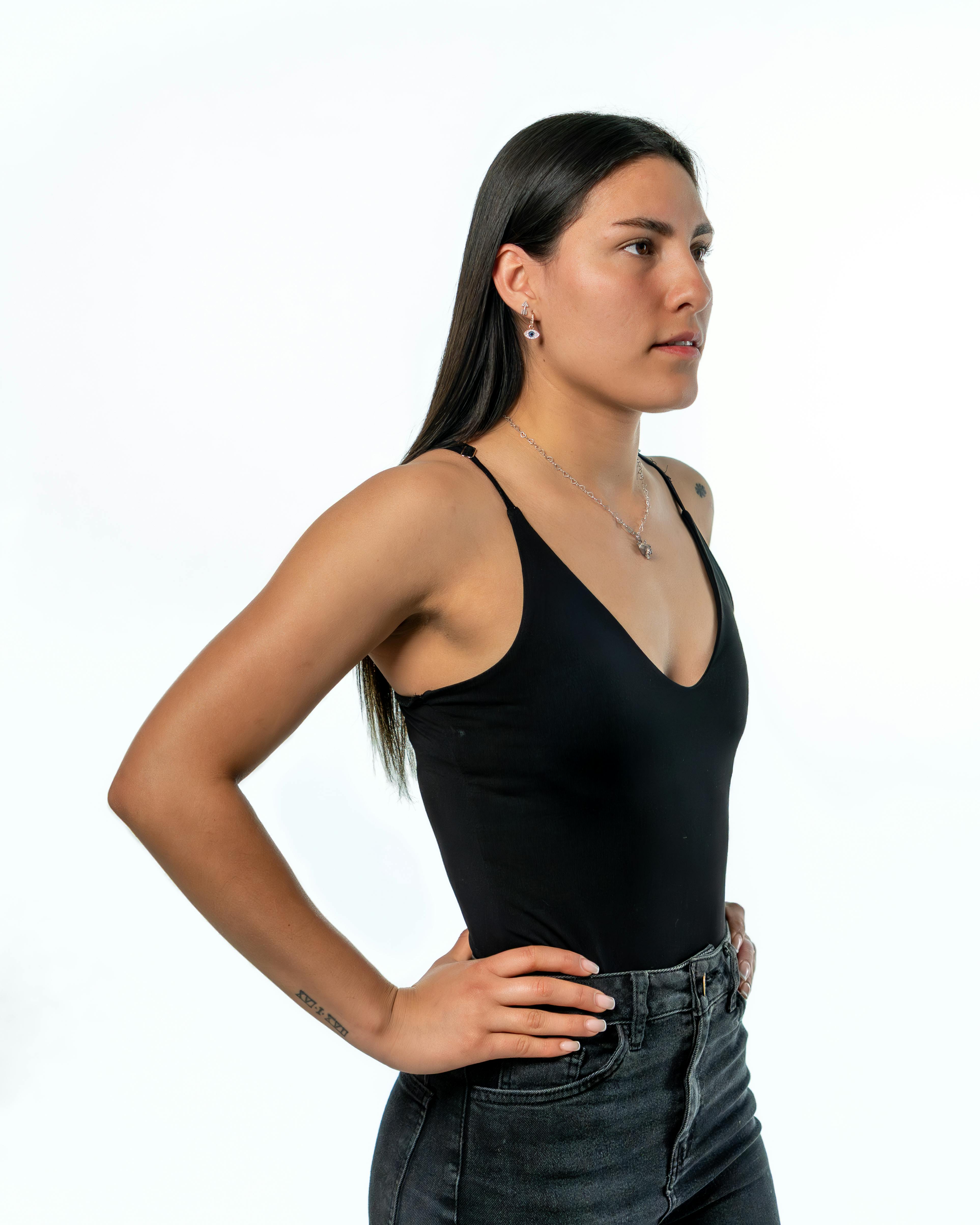 Confident woman posing in a black top against a clean white background.