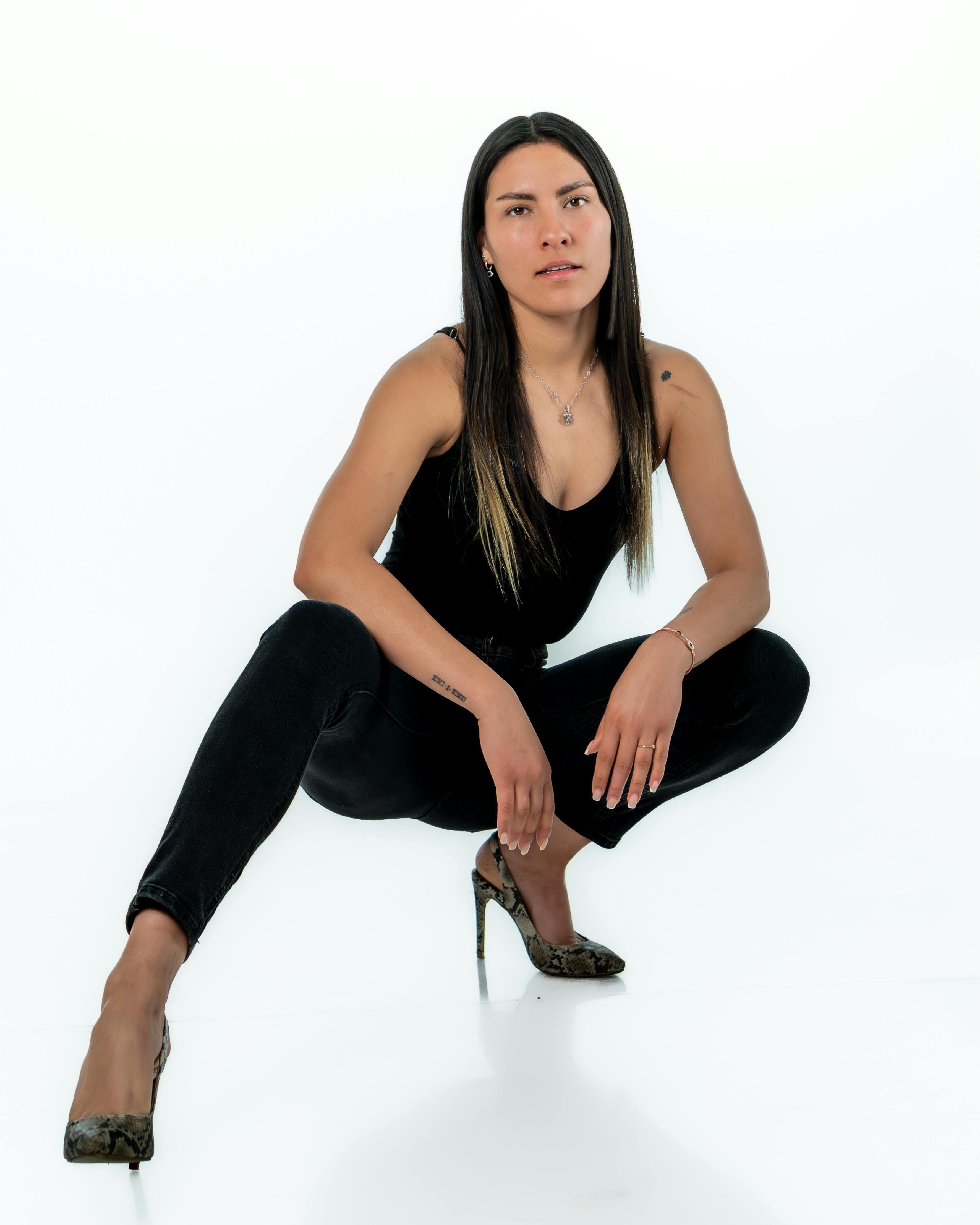 bezplatná Elegantní žena ve stylovém černém oblečení pózuje výrazně ve studiu. Základová fotografie