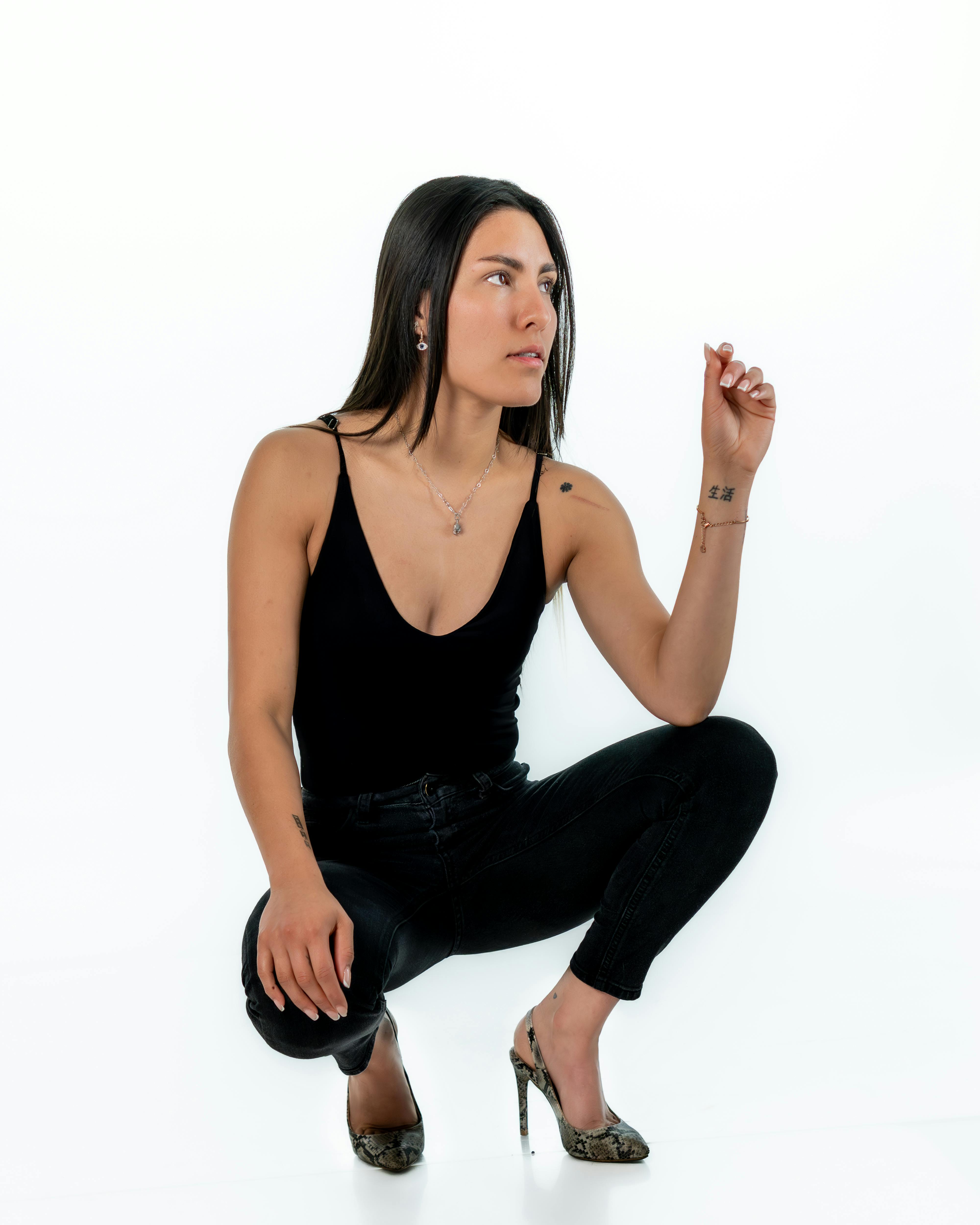 Gratis Potret seorang wanita bergaya dalam pakaian hitam, berpose dengan percaya diri dengan latar belakang putih. Foto Stok