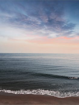 泰国海滩的清晨宁静祥和，海浪平静，日出色彩充满活力