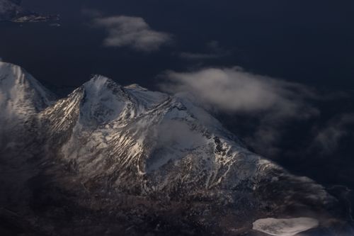 Free Aerial view of snow-covered mountains in Tromsø, Norway, during winter's dramatic dusk. Stock Photo