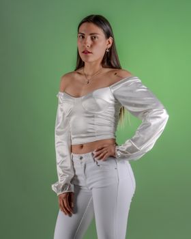 Portrait of a young woman in a white satin top with a vibrant green background.