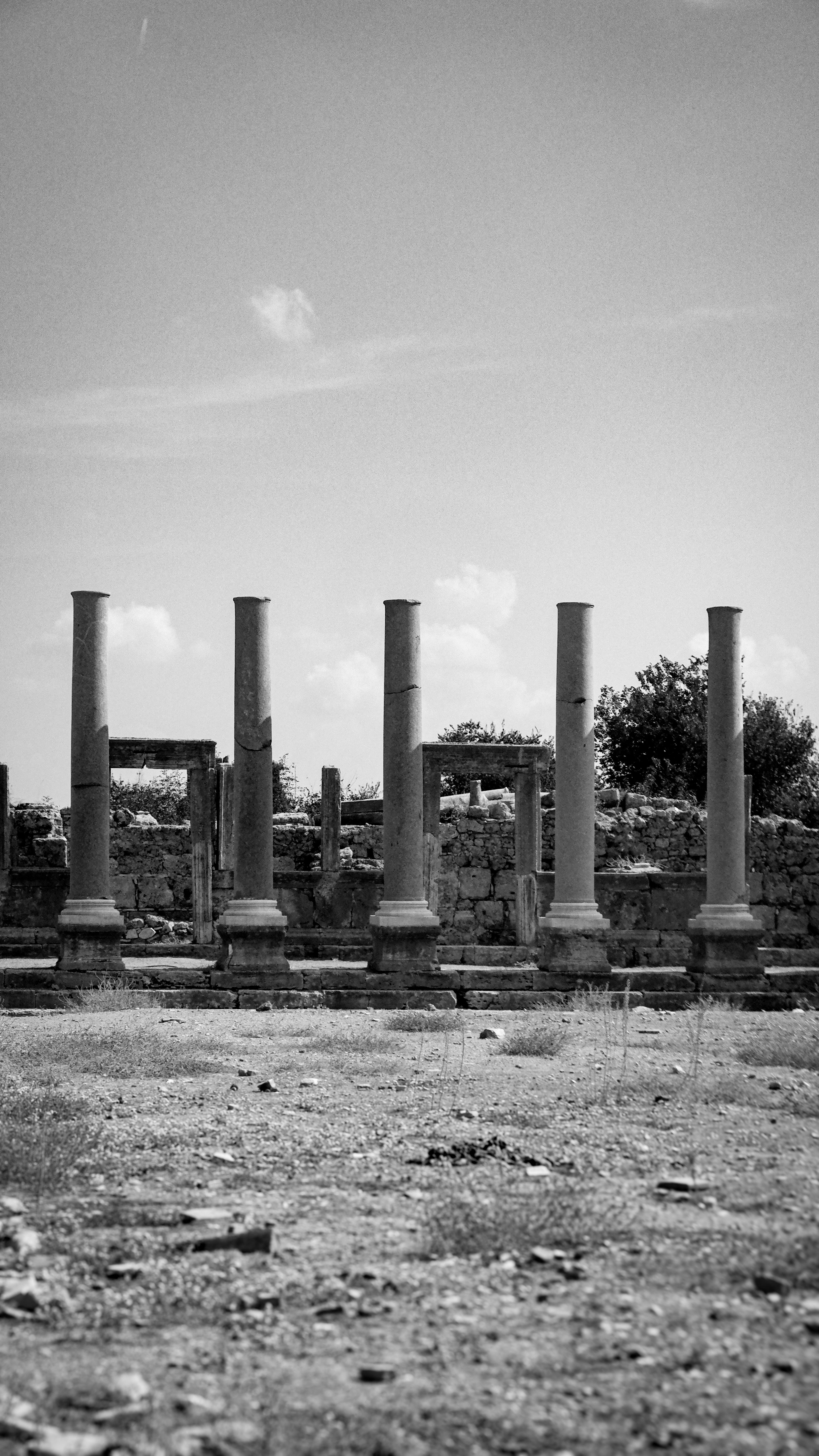 Black and white photo of ancient stone columns against a partly cloudy sky.
