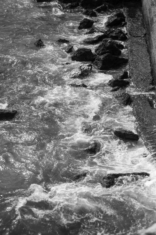 Free Monochrome image of ocean waves crashing against rocky shoreline. Captures motion and texture. Stock Photo