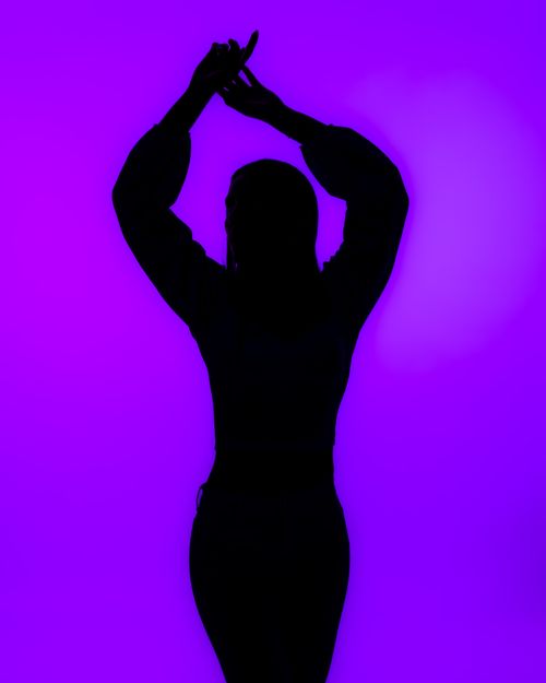 Free Artistic silhouette of a woman posing gracefully against a vivid purple backdrop. Stock Photo