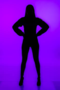 Silhouette of a woman striking an empowering pose against a vibrant purple backdrop.