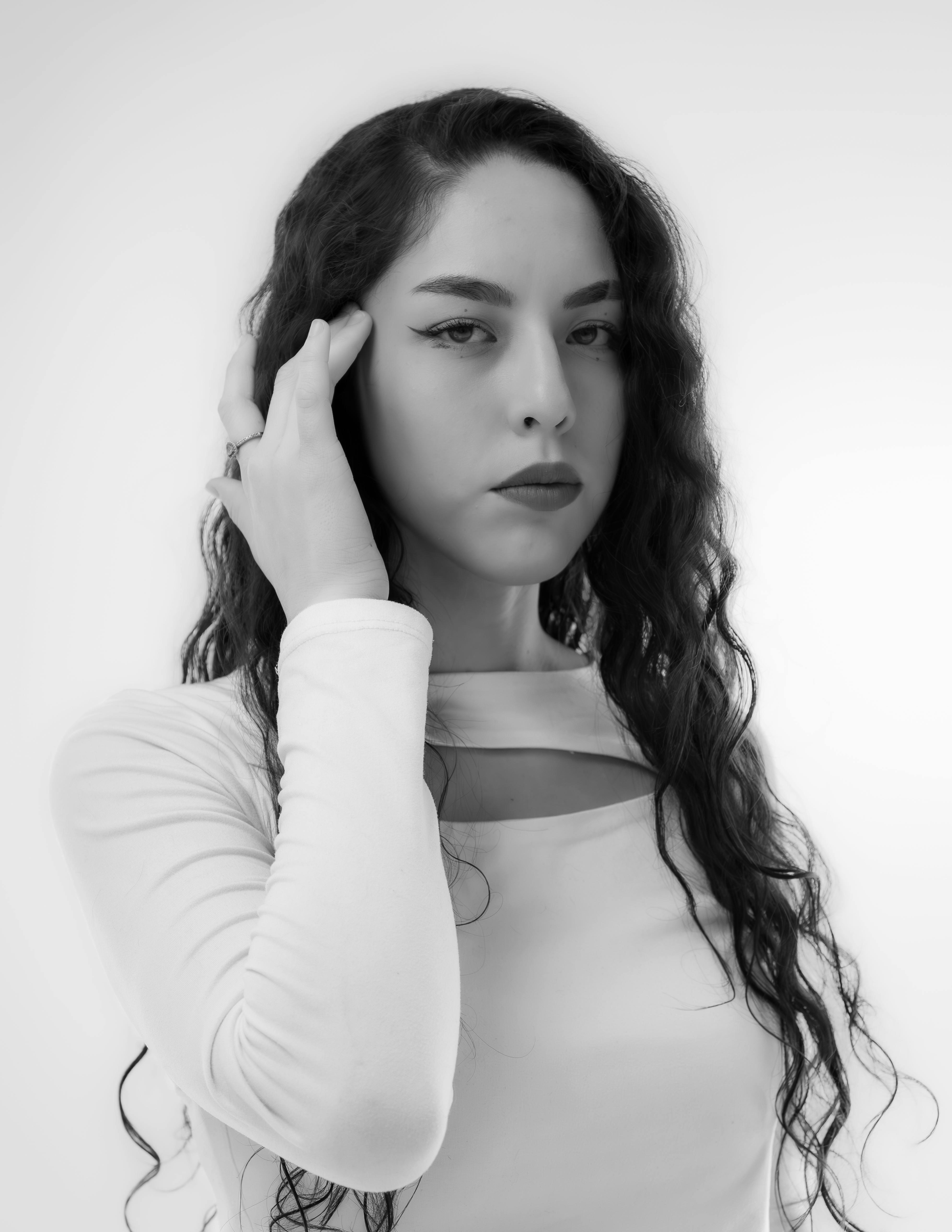 grátis Um impressionante retrato em preto e branco mostrando uma mulher confiante com cabelos longos em uma pose artística. Foto profissional