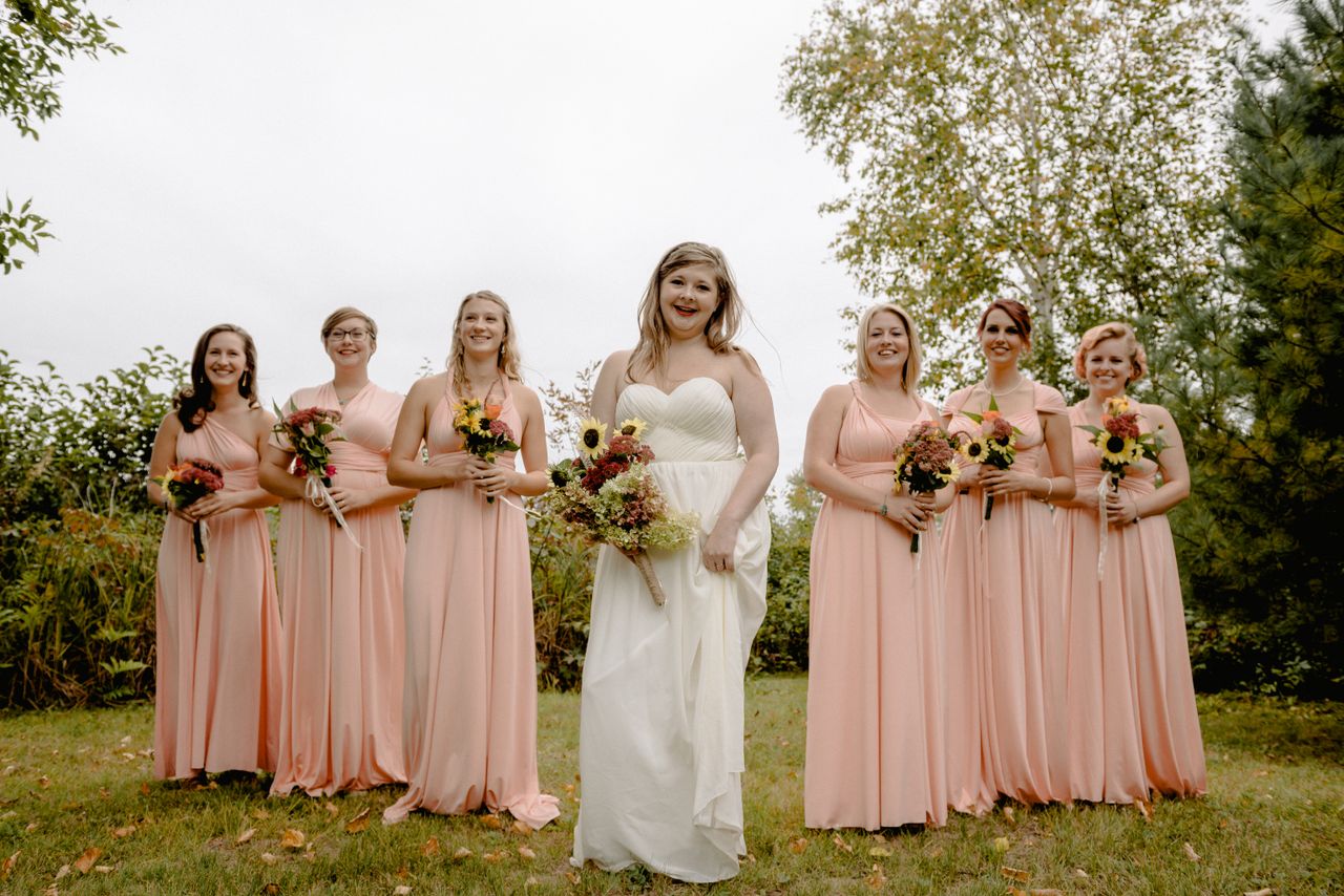 Bride and bridesmaids in dusty rose and blush dresses at an outdoor wedding ceremony