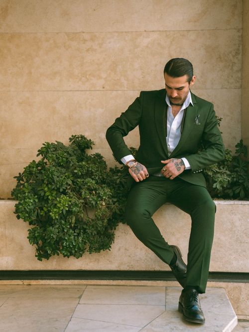 Free Fashionable man in green suit sitting outdoors, showcasing tattoos and modern style. Stock Photo