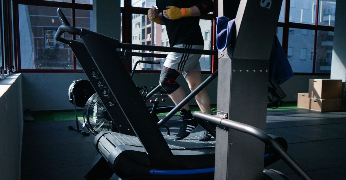 Adult man exercising on a treadmill in a modern indoor gym setting.