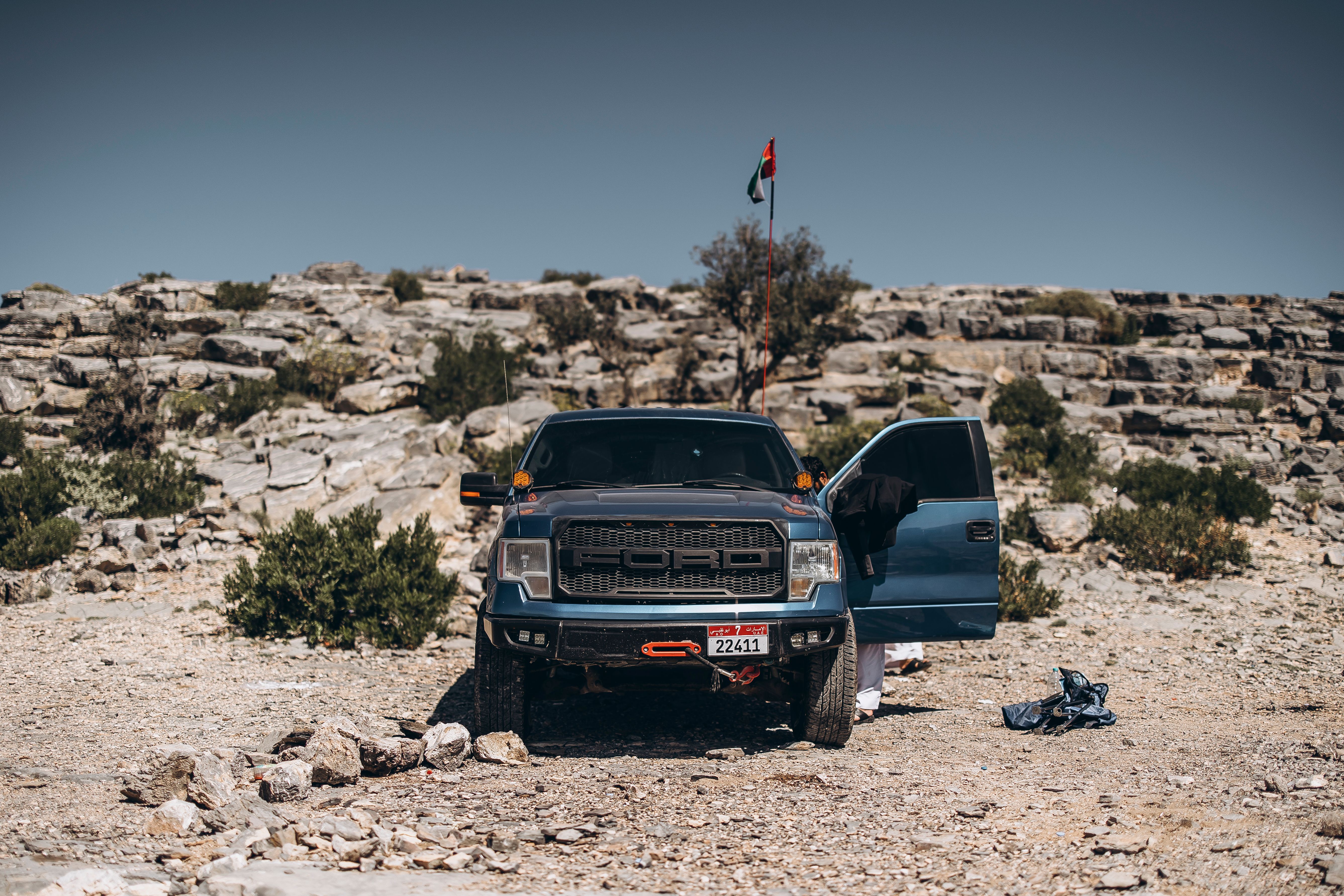 Off-road truck adventure in Oman's rocky desert landscape under clear skies.