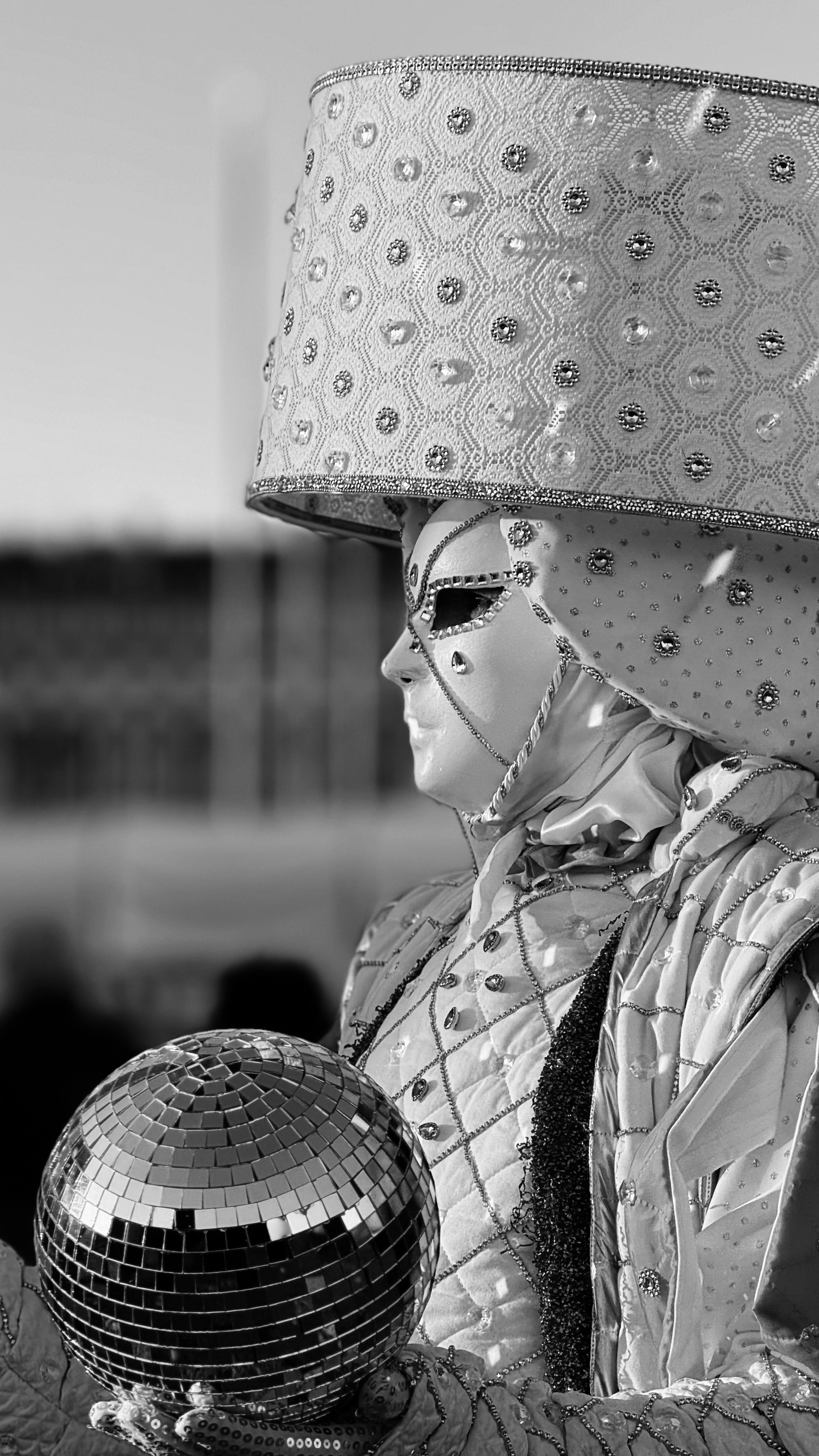 A mysterious costumed figure holding a disco ball, emphasizing elegance and intrigue.