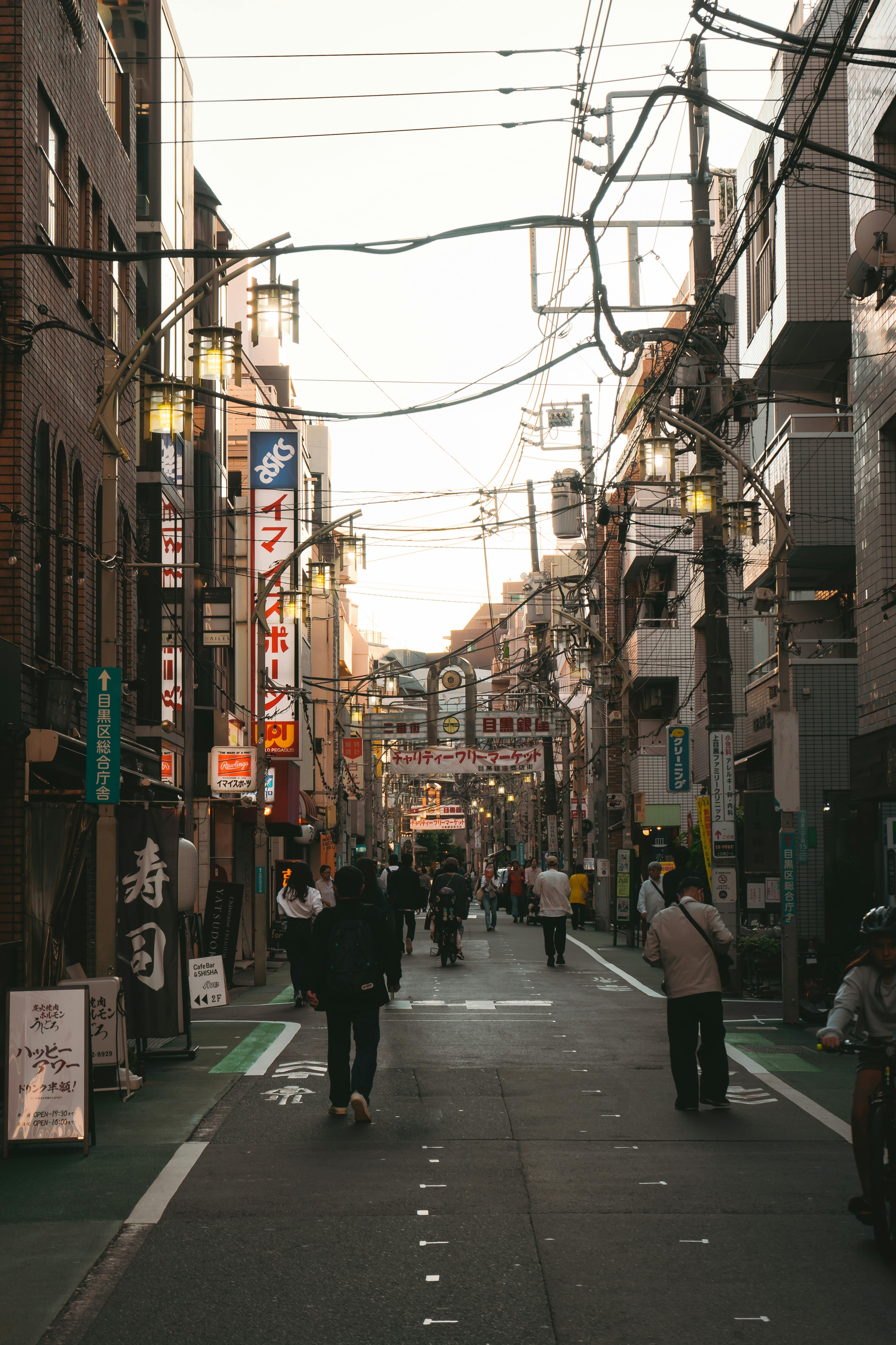 Vibrant urban street in Japan with pedestrians, shops, and signage during daytime.