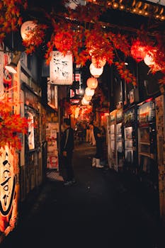 Captivating night view of a bustling alleyway in Tokyo, adorned with lanterns and autumn leaves.