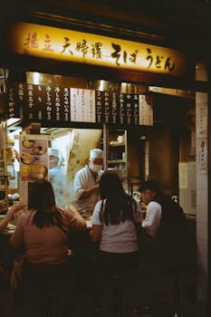 Customers enjoy soba noodles at a traditional udon shop in Japan, captured during a busy evening.
