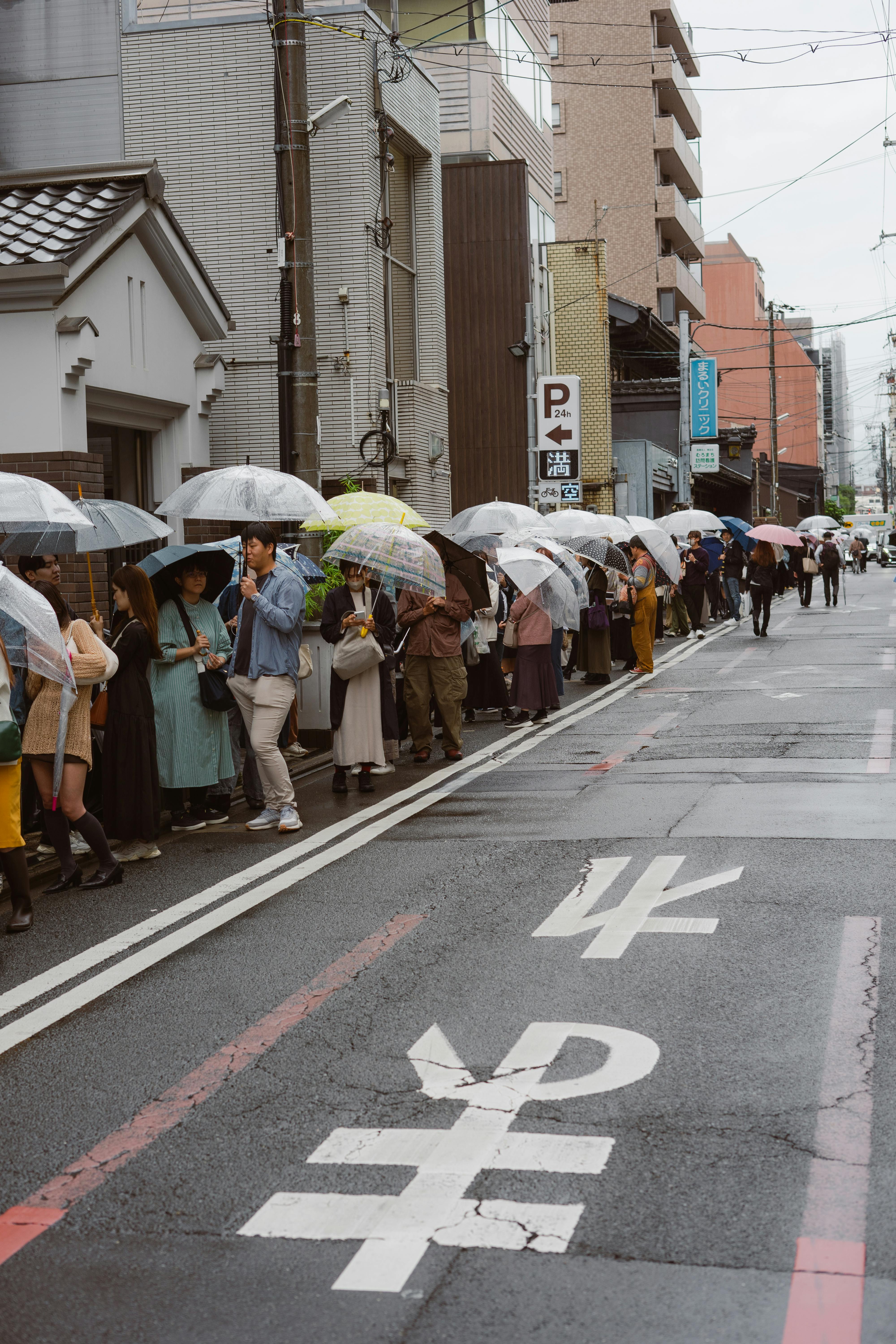 A line of people with umbrellas on a rainy street in Japan, showcasing urban life.