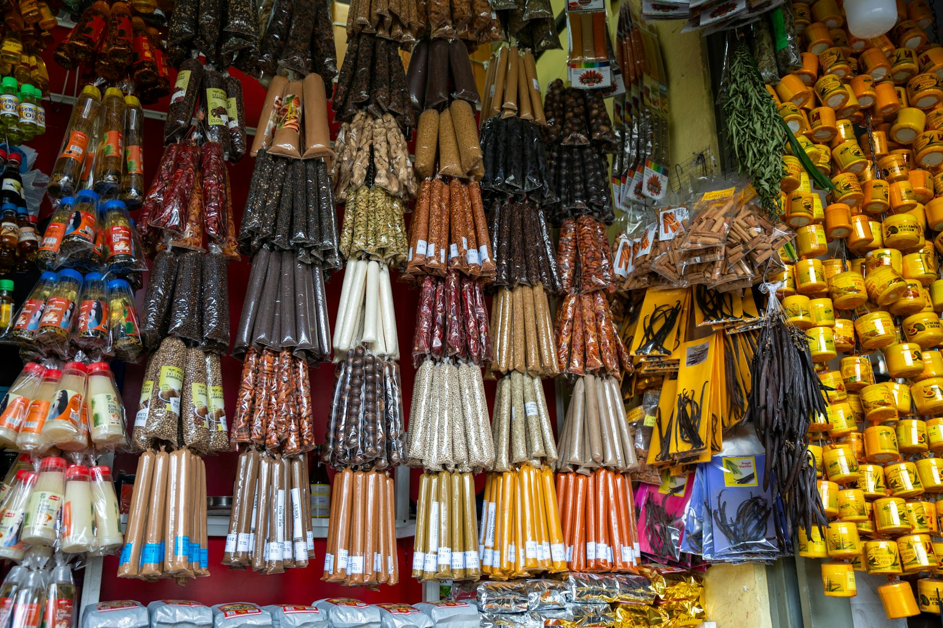 Vibrant market stall with a variety of spices, candles, and packaged goods on display.