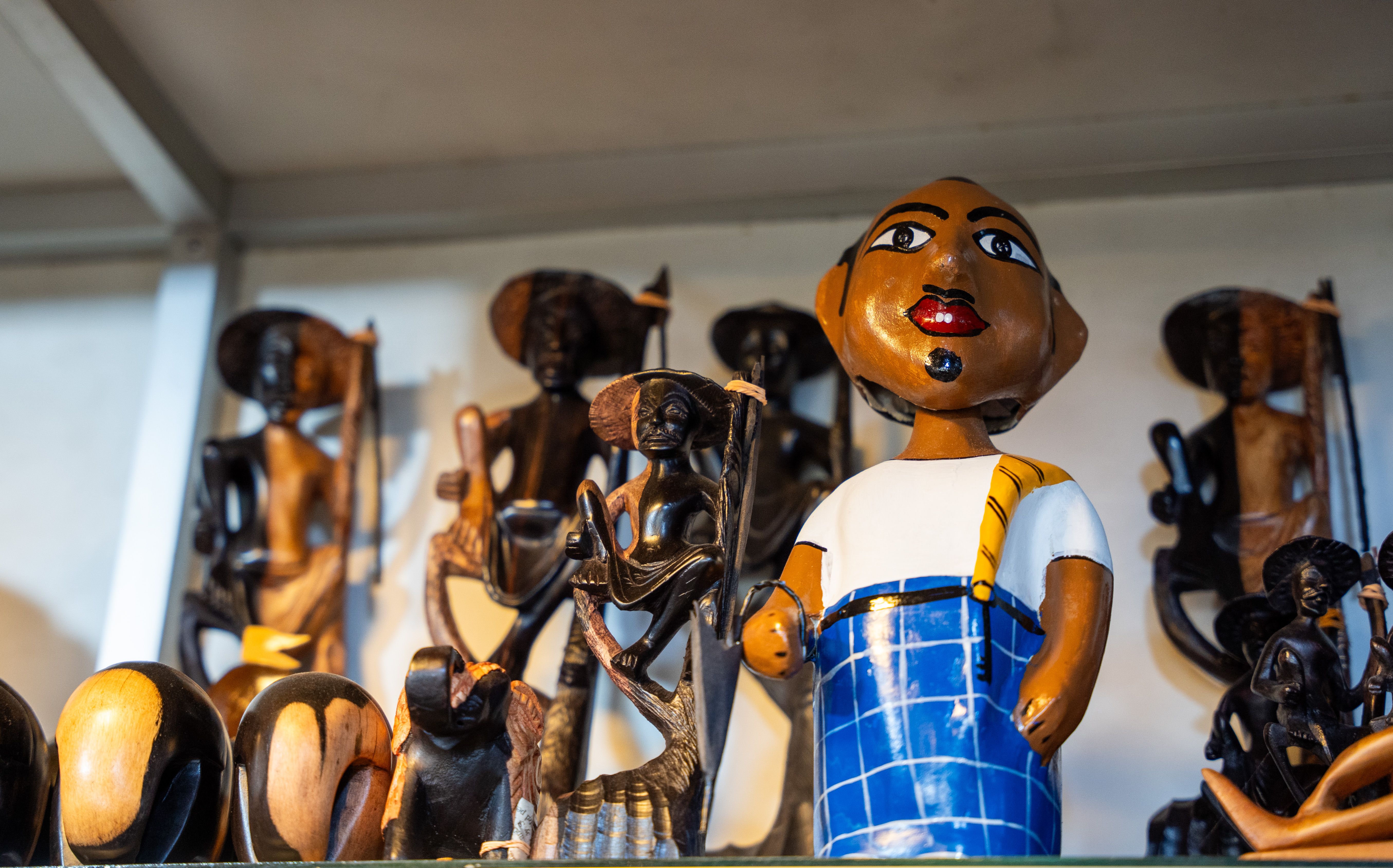 Vibrant wooden African figurines displayed on a shelf, capturing cultural craftsmanship.