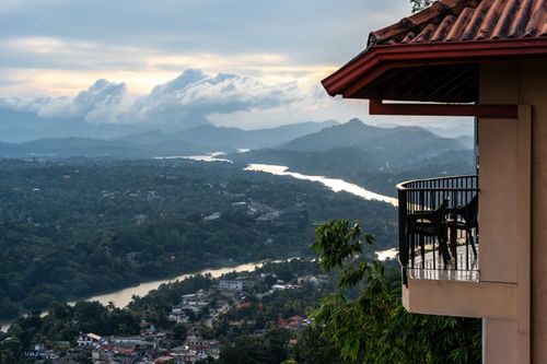 Free Picturesque view from a cozy balcony overlooking a lush valley and winding river at twilight. Stock Photo