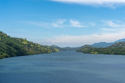 Free Stunning river surrounded by lush hills under a clear blue sky, showcasing serene nature. Stock Photo