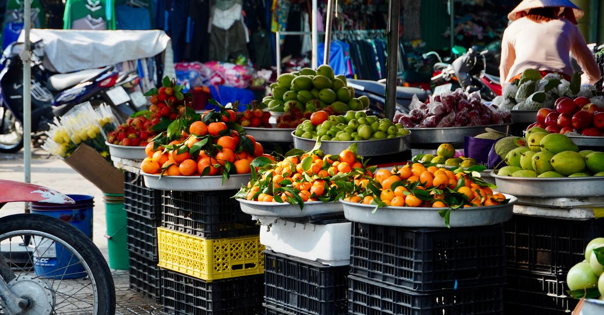 A busy outdoor market with fresh fruits and vegetables in baskets