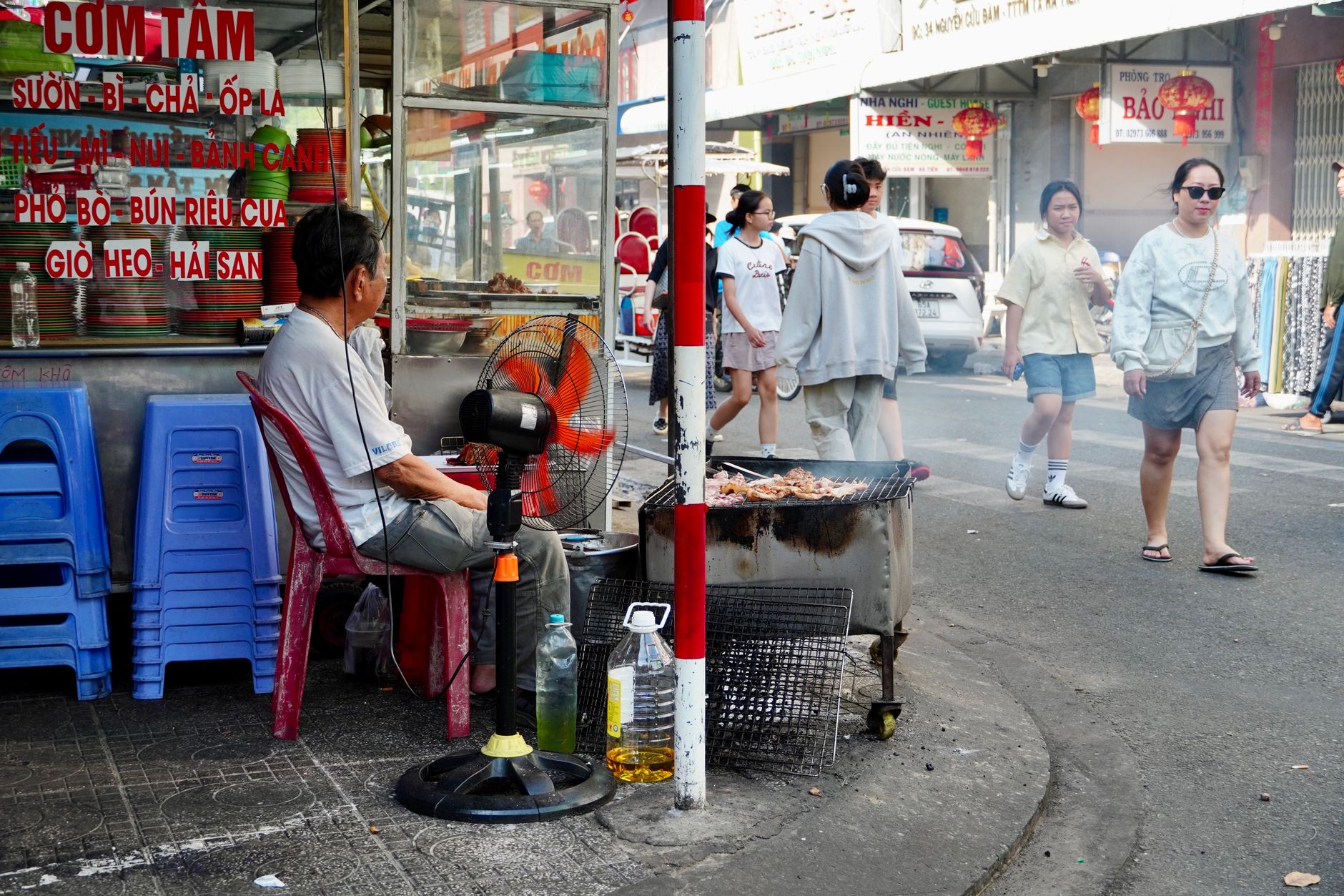 Grillverkäufer in einer belebten Straße in Ho Chi Minh City mit Fußgängern.