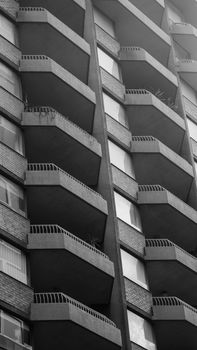 Monochrome view of a modern high-rise building with geometric balconies and minimalist design.