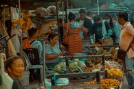 A bustling street market showcasing colorful fruits, vegetables, and vibrant interactions among diverse vendors and customers.