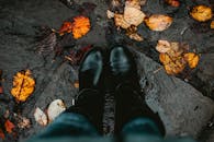 两双黑色靴子走在潮湿、铺满落叶的石路上，捕捉到了秋天的精髓
