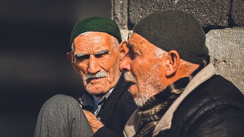 Free Two senior men in knit caps having a conversation outdoors with warm sunlight. Stock Photo