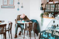 一位老人坐在咖啡馆里，在舒适的装饰和灯光环绕下，伏案写作