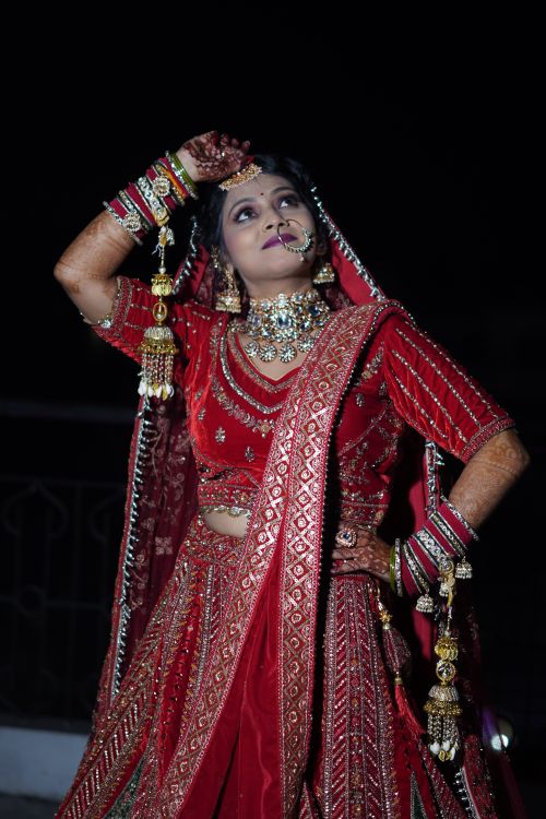 Free A stunning Indian bride poses gracefully in ornate red and gold bridal wear with intricate jewelry. Stock Photo
