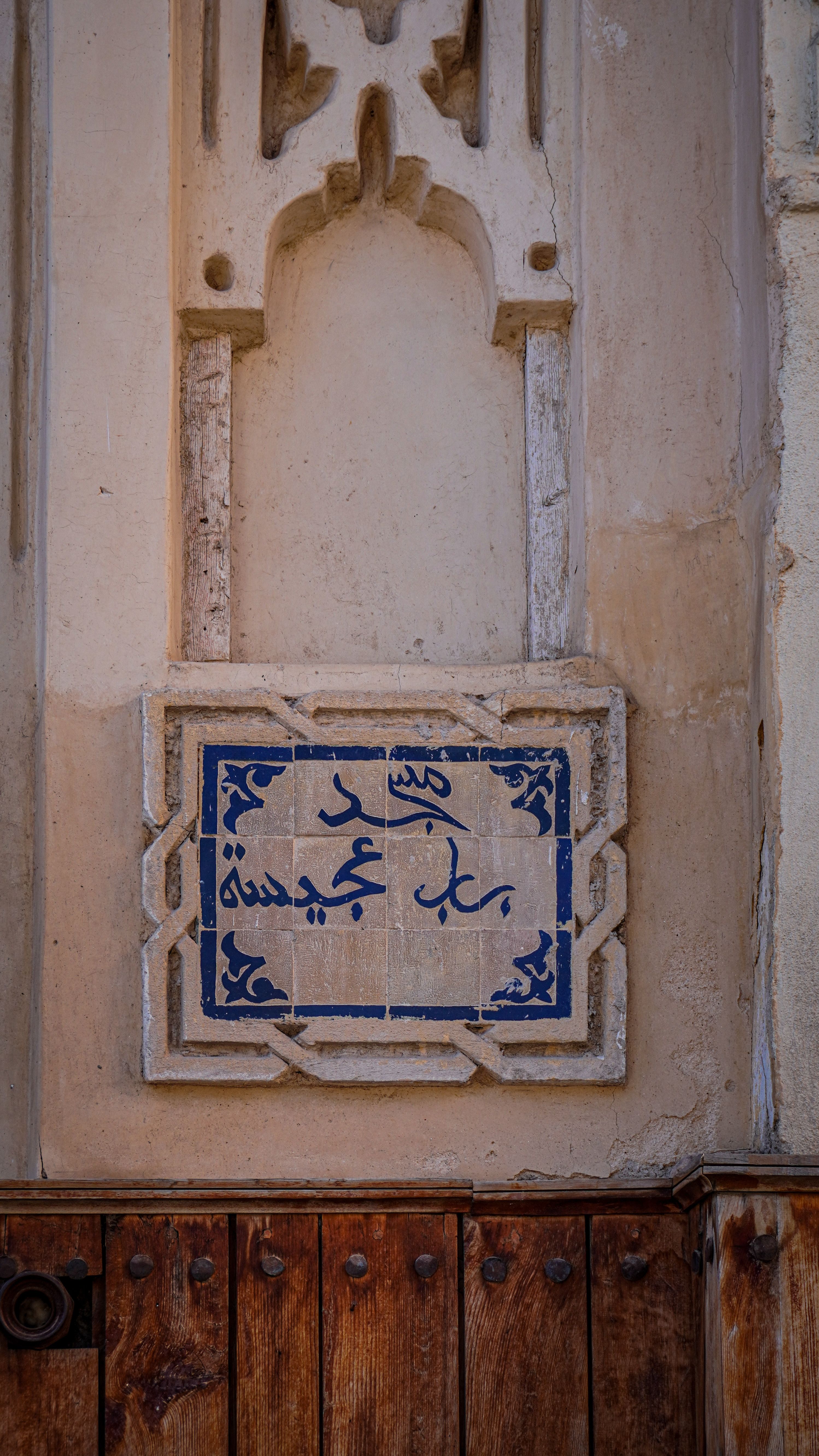 Close-up of blue Arabic inscription on a traditional wall in Fes, Morocco.